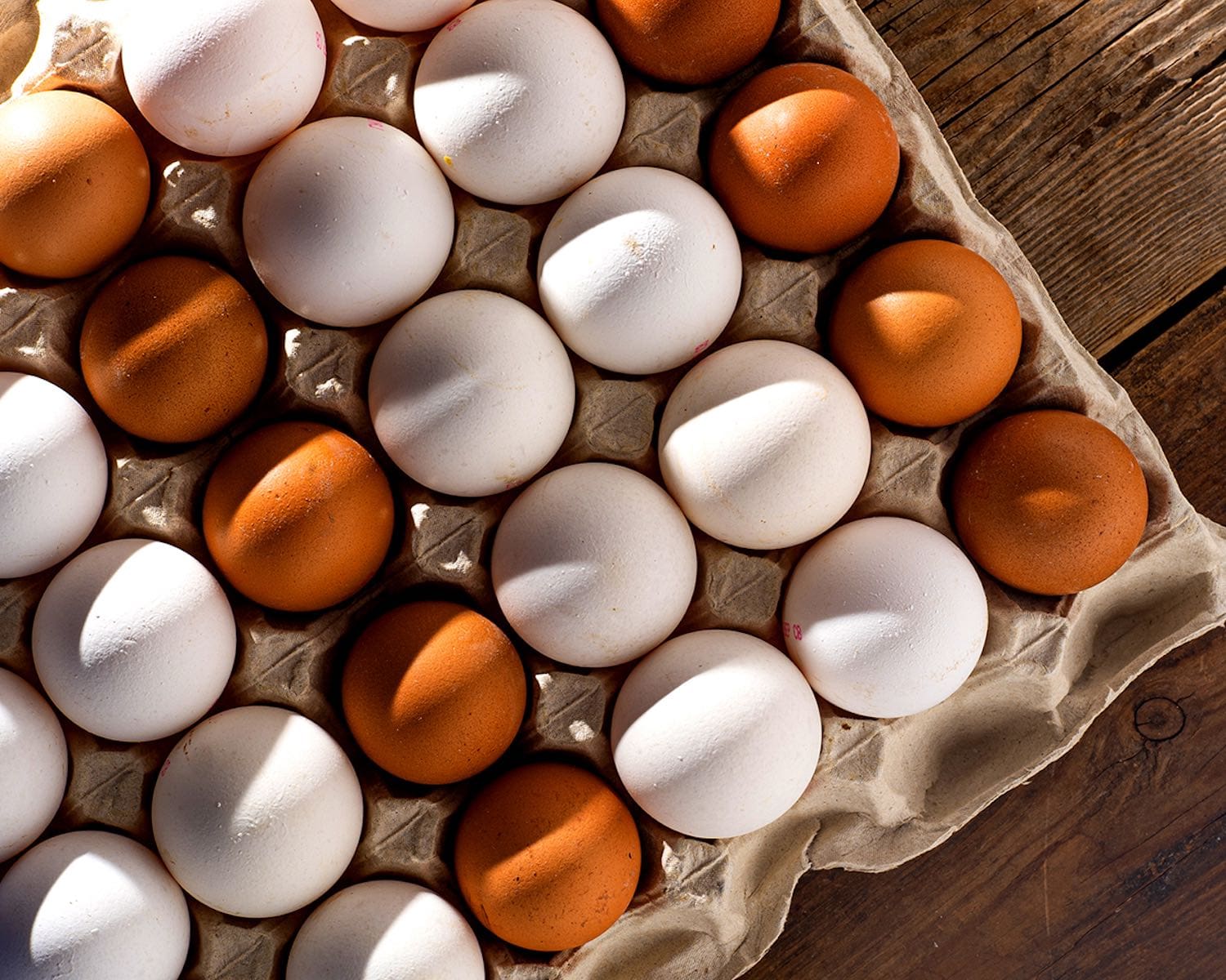 White and brown eggs in a paper box tray