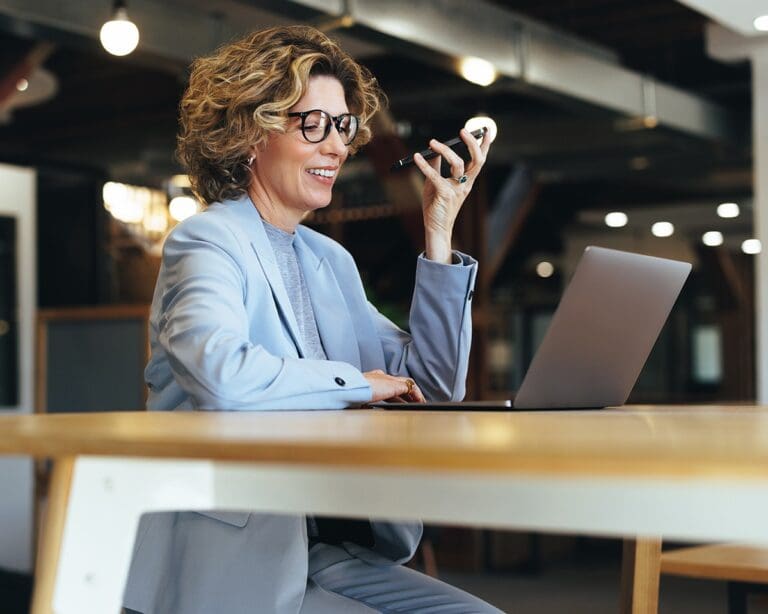 Woman talking on a phone call while working on a laptop